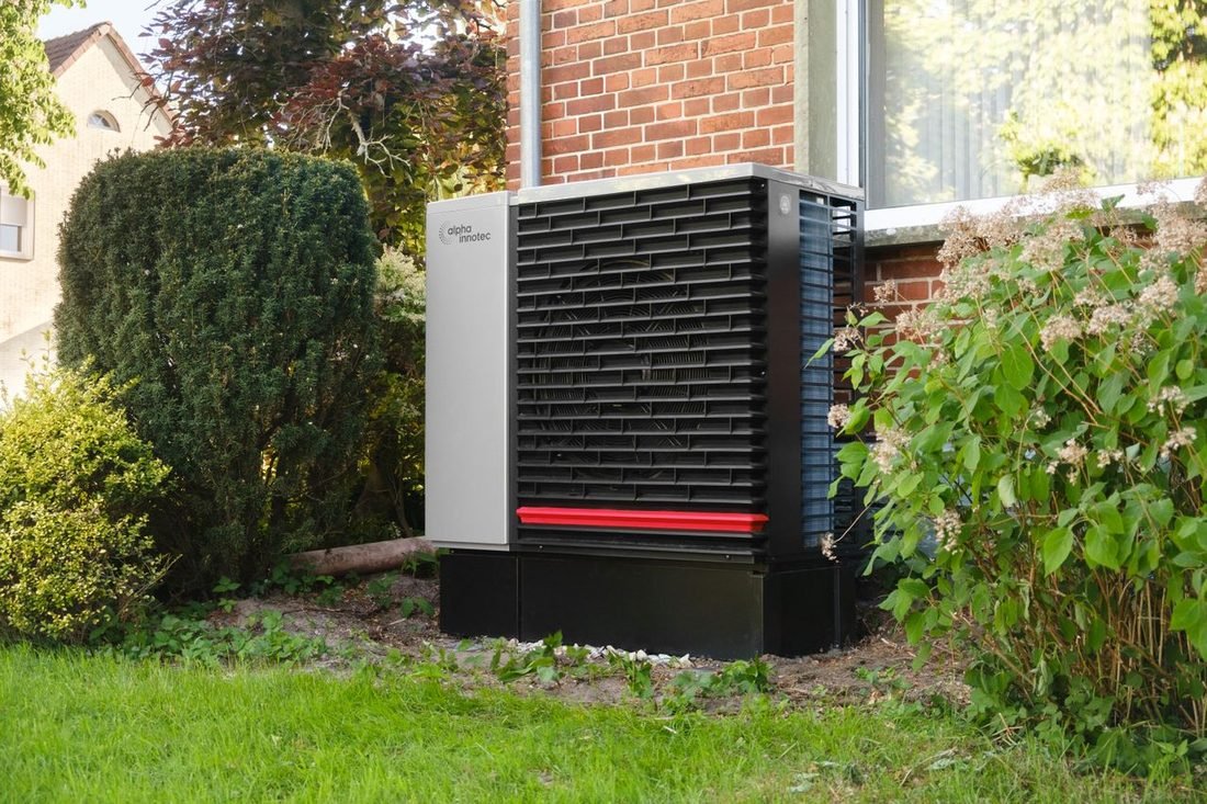 Moderne Wärmepumpe an einem Einfamilienhaus im Garten